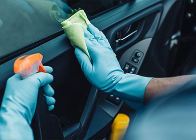 gloved hands cleaning interior car door panel