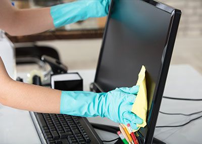 gloved hands cleaning computer monitor
