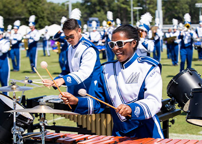 Students in the marching band performing with xylophones, drums, and more instruments. 