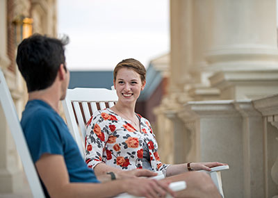 Two students sitting in rocking chairs outside Trible Library 