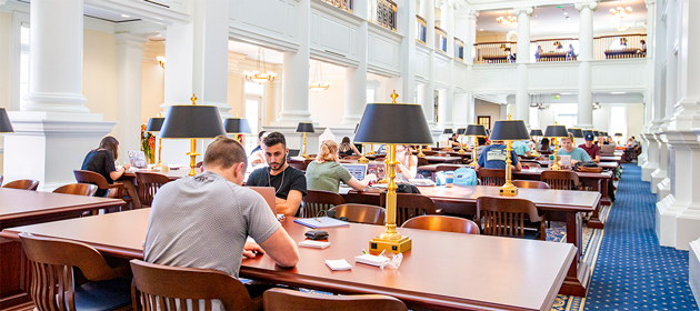 Students sit at tables in the Rosemary Reading Room inside of the Trible Library at Christopher Newport University.