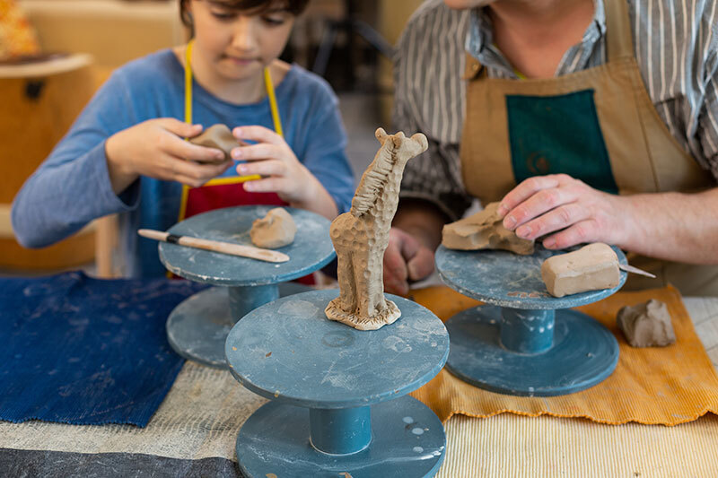 Child and teacher sculpting clay animals