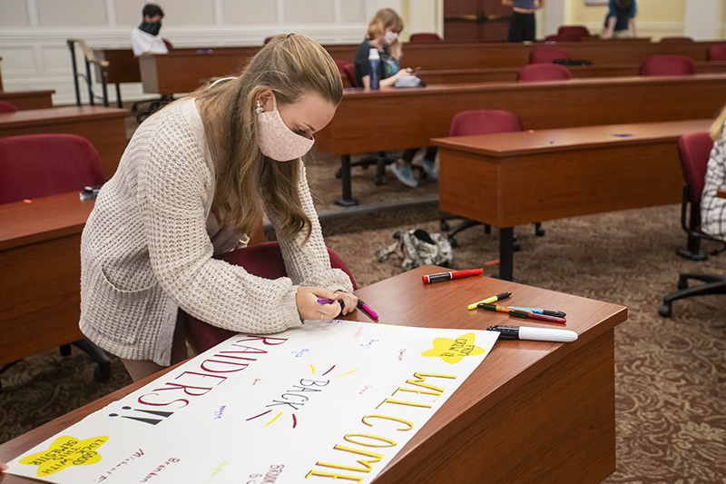 A student writes on a poster for Newport News Public Schools students