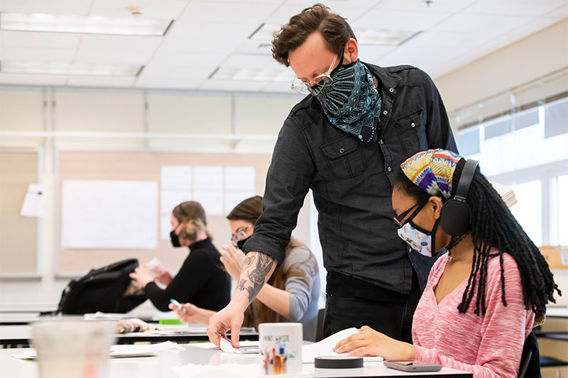 Ryan Lytle (standing) works with a student in the classroom