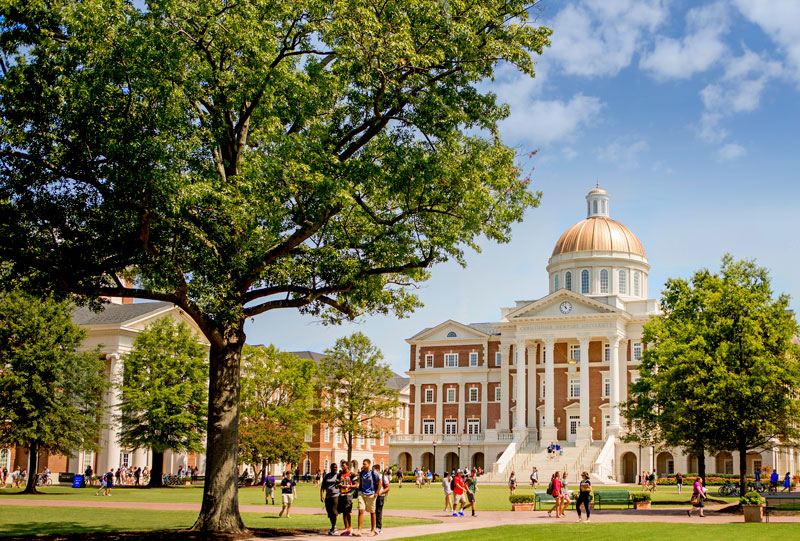 Students walk on the Great Lawn with Christopher Newport Hall in the background