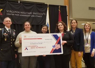 A VMI conference judge with Christopher Newport students and staff holding an oversized check