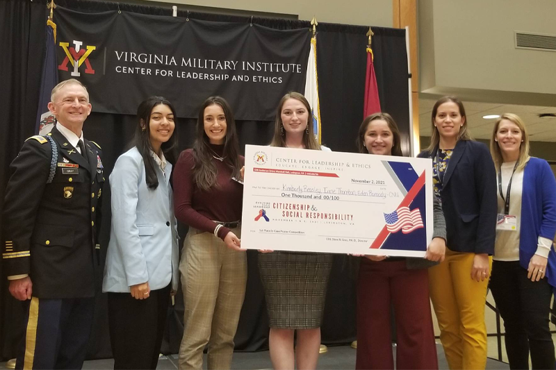 A VMI conference judge with Christopher Newport students and staff holding an oversized check