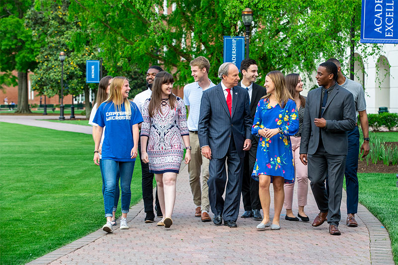 President Paul Trible (center) walks with students on the Great Lawn in 2019.