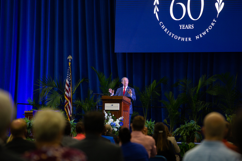 President Trible on stage at a lectern addressing an audience of CNU faculty and staff
