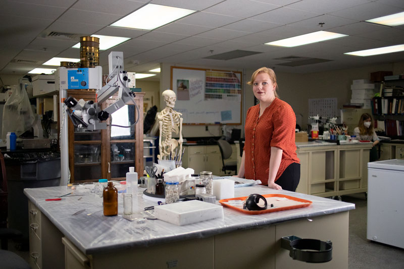 Photo of Chelsea Blake in her lab surrounded by equipment at the Virginia Department of Historic Resources