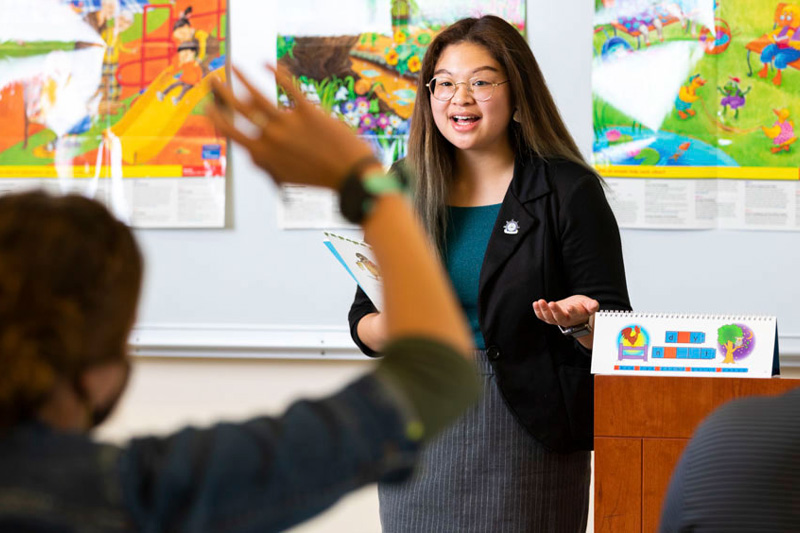 A teaching student presenting at the head of her classroom