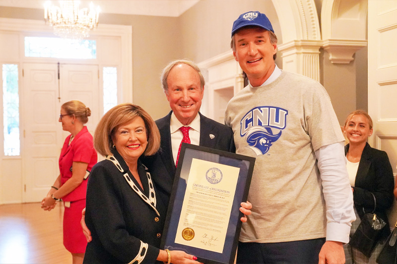 Paul and Rosemary Trible standing in the Governor's mansion with Governor Glenn Youngkin and holding the framed proclamation for Paul Trible Day