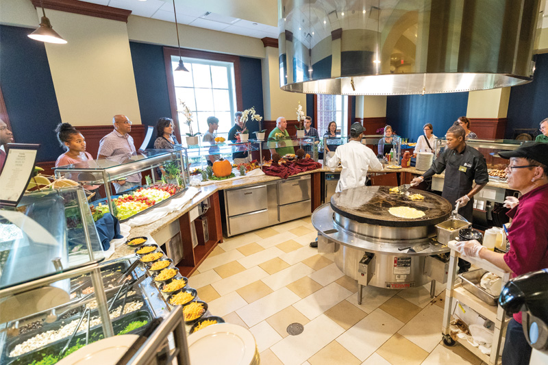 A wide-angle shot of the omelet station line in Regattas with staff serving waiting guests.