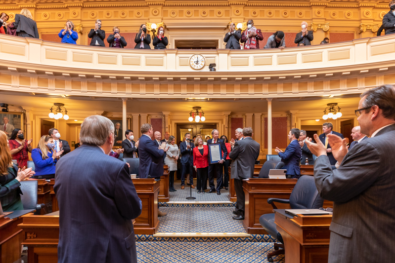 Photo of Virginia lawmakers applauding Paul and Rosemary Trible after they receive the framed joint resolution