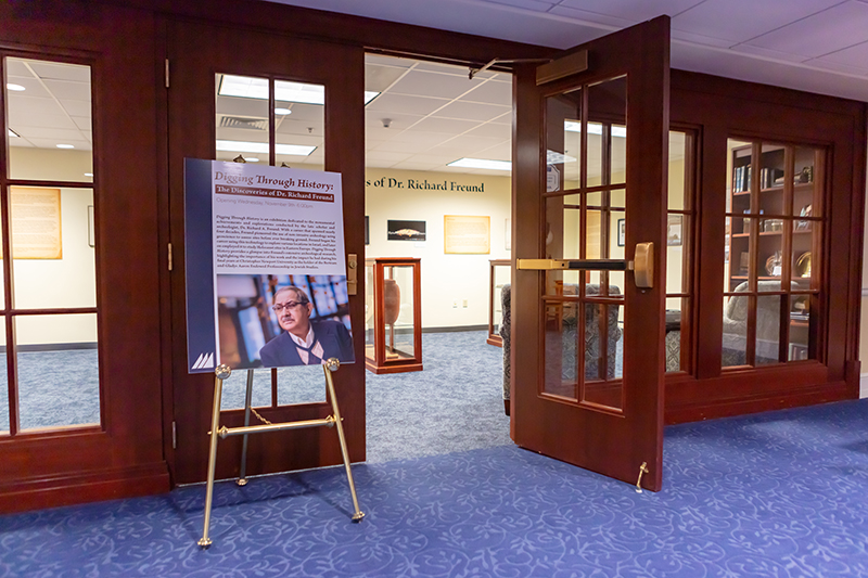 A poster that talks about the life and resesarch of former CNU professor Dr. Richard Freund stands on an easel outside of the exhibition in the Trible Library.