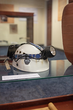 A hard hat with a headlamp belonging to professor Dr. Richard Freund sits on a glass shelf.