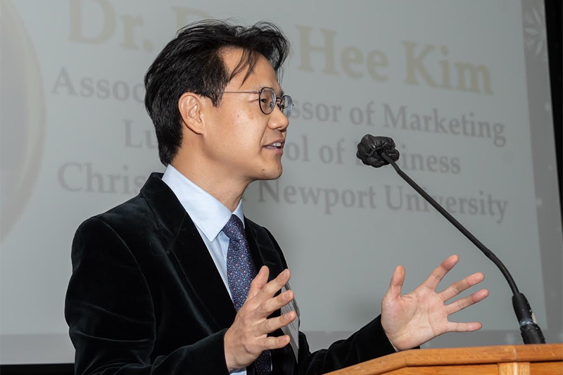 Dr. Dae-Hee Kim stands at a podium during a presentation.