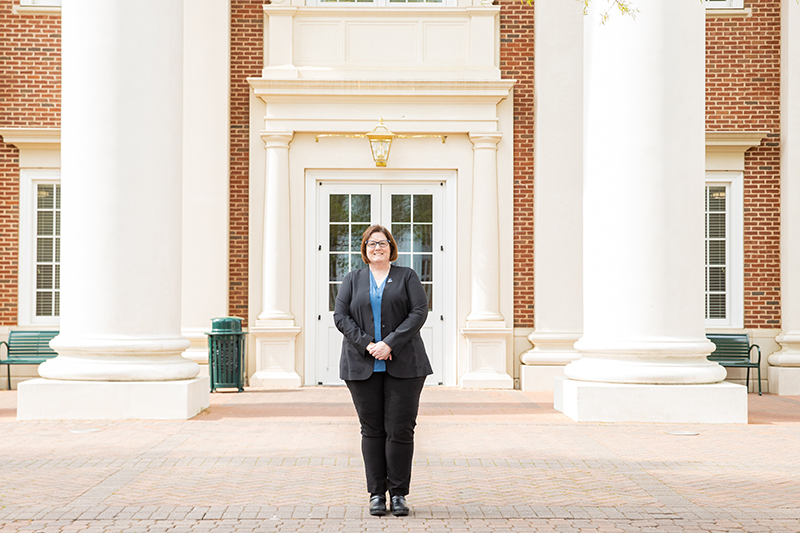 Associate Professor Linda Ficht stands in front of a building on campus.