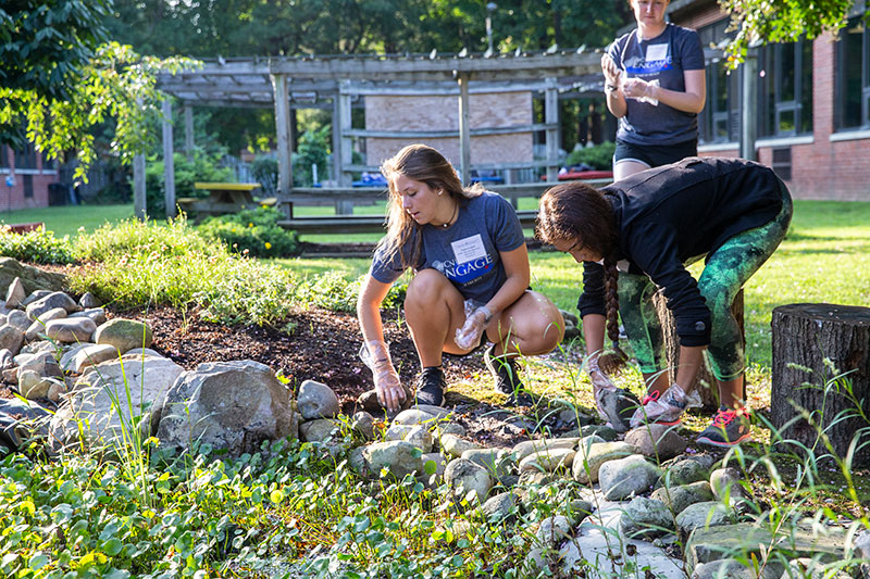 A group of students perform landscaping duties in a garden.