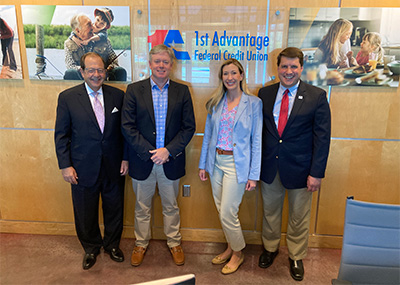 Four individuals stand in front of a sign for 1st Advantage Federal Credit Union