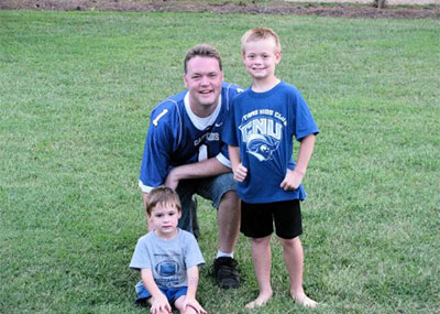 Two young boys pose with a member of Christopher Newport's football team.