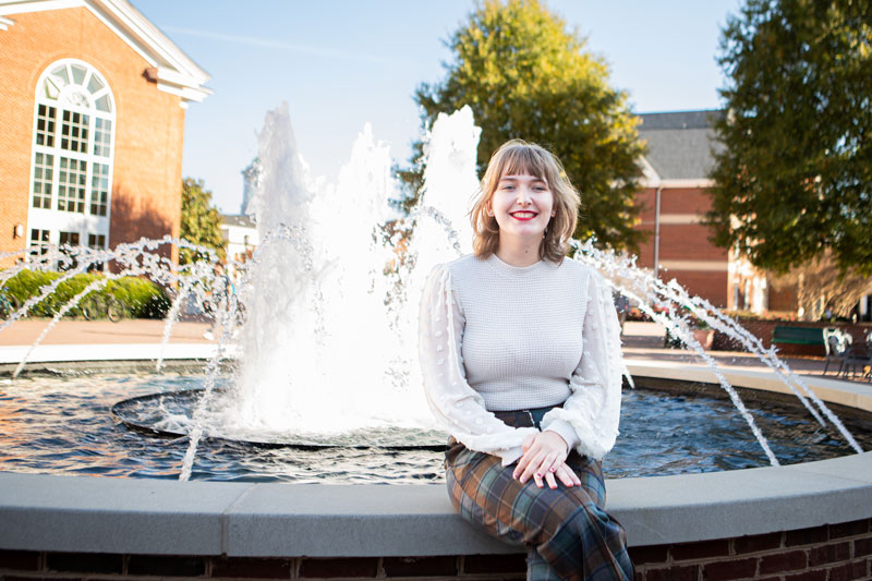 Abi Sloniker sits with a fountain behind her.