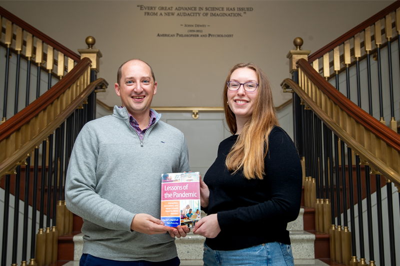 Dr. Tim Pressley and Kyla Ganey hold up a copy of a book they worked on together.