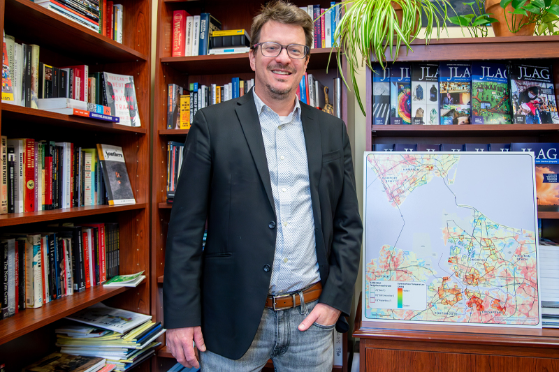 Dr. John Finns stands in his office next to a map of Hampton Roads.