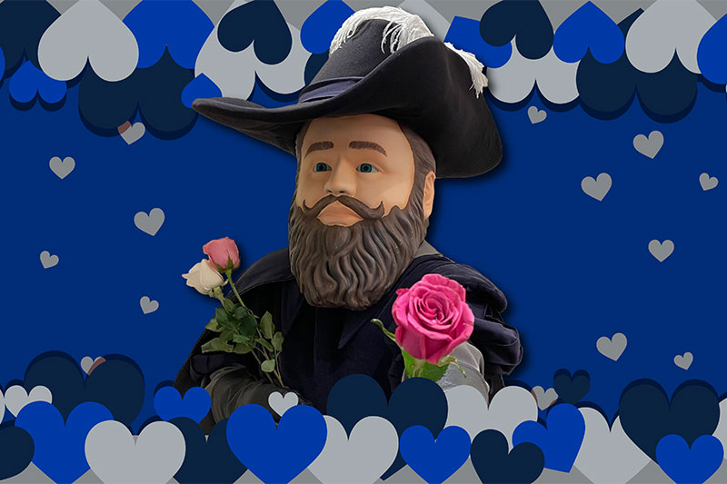 Various shades of blue and gray hearts line the top and bottom of the image. In the center is Captain Chris, with one hand holding two roses, one white and one light pink against his chest. One hand is extended offering a bright pink rose.