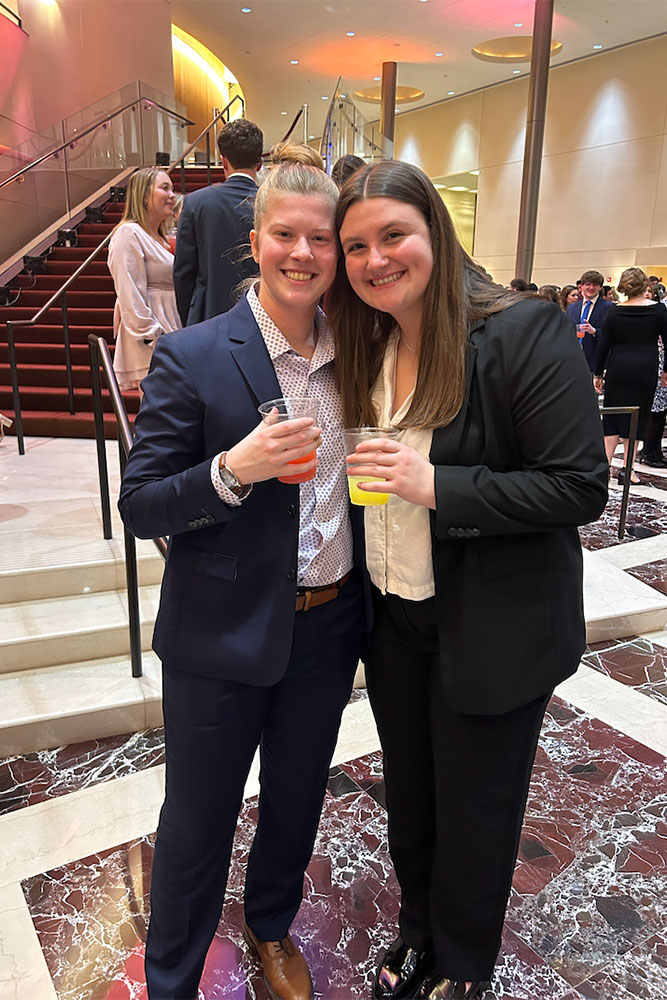 Erin and Morgan in business attire holding drinks