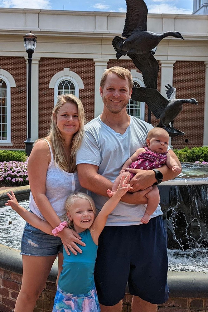 Juliana and Nick stand in front of the Goose Fountain with their two daughters Felicity and Zoey