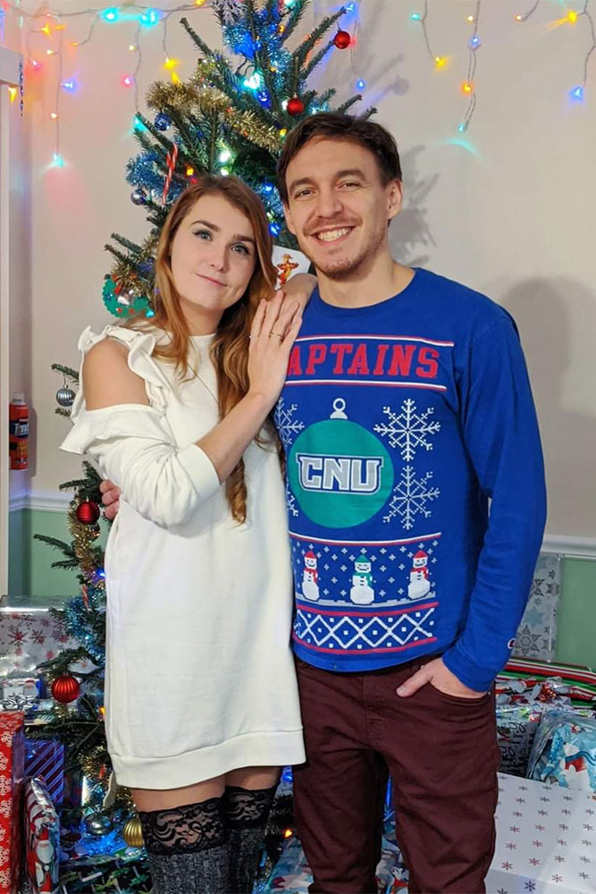 Olga and Adin stand in front of a Christmas tree