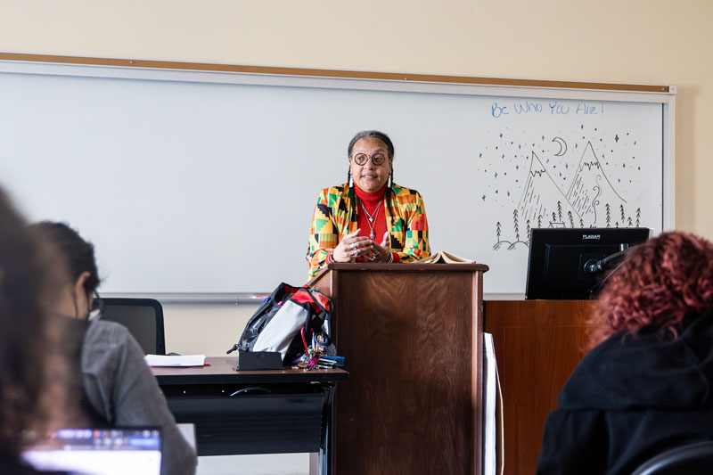 Dr. Pat Hopkins stands at the lecturn while addressing students in her class.