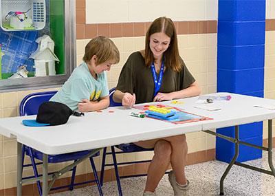 A CNU student sits at a table with an elementary school student.