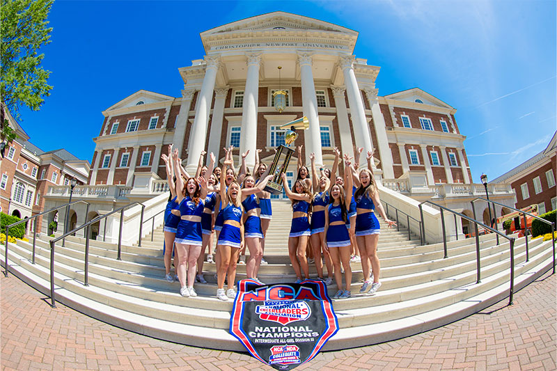 Cheerleading team smiling and posing with national championship trophy