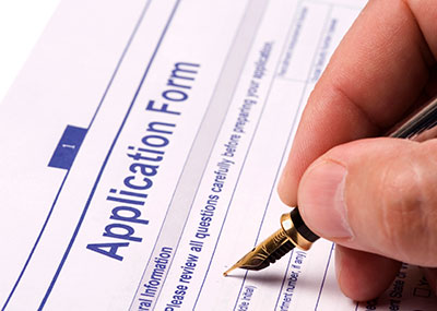 Hand holding a pen, filling out an application form