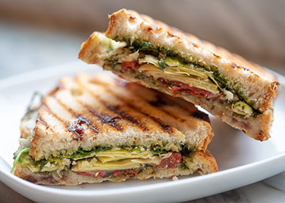 Basil, tomato and cheese panini sandwich on a white plate