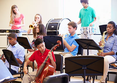 Students sitting in chairs playing various musical instruments.