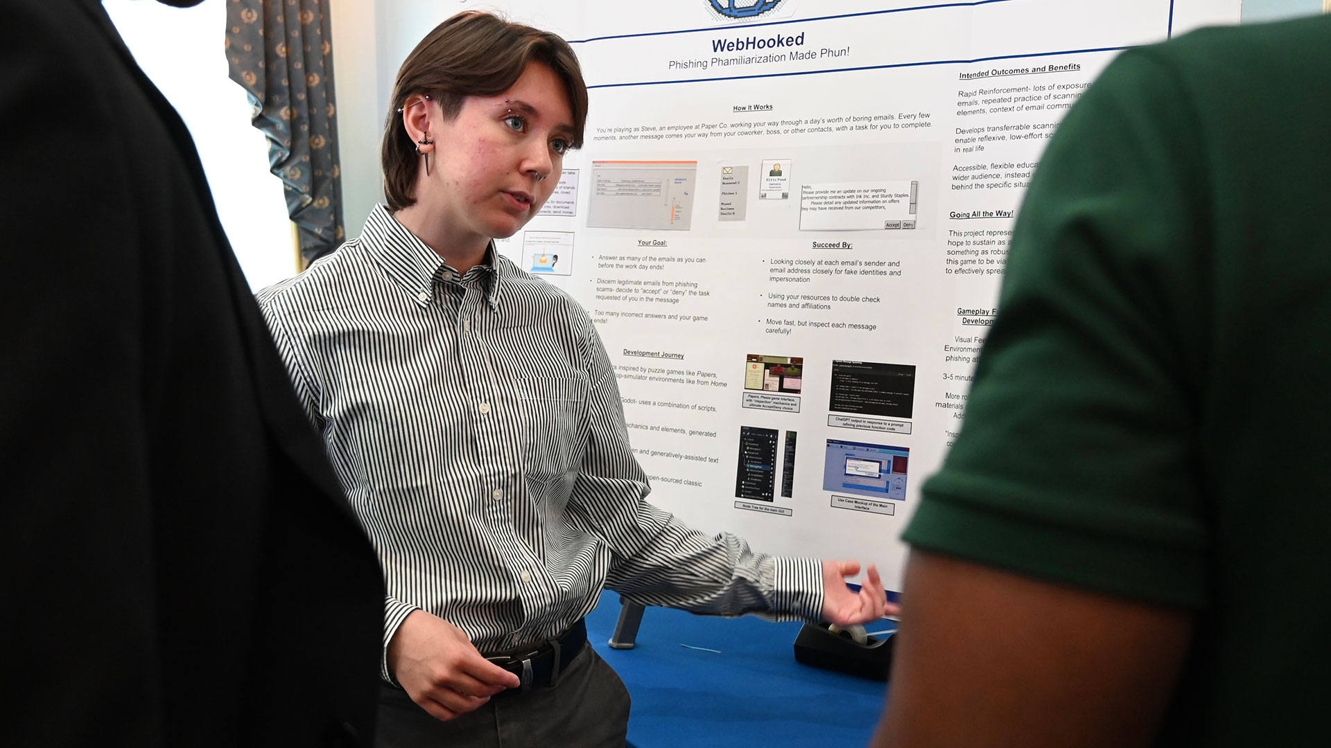 A student stands in front of a poster board of their research while talking to people