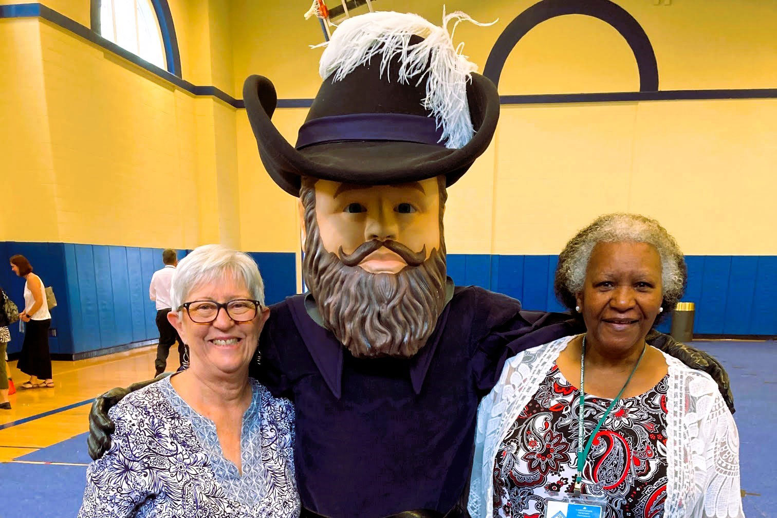 Two women stand on either side of CNU mascot Captain Chris