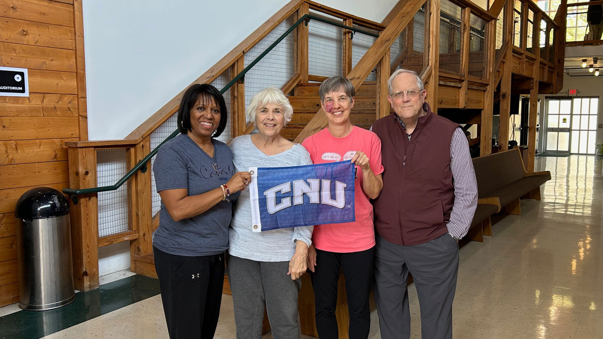 A group of Lifelong Learning Society members hold a blue CNU flag