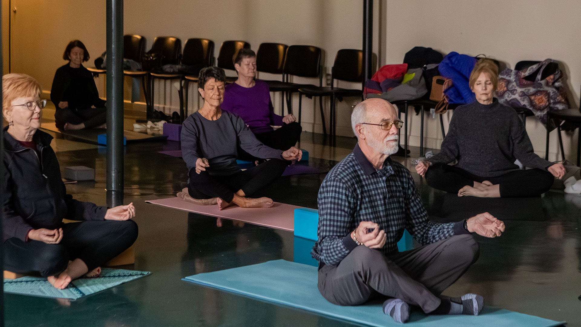 Lifelong Learning society members sit on yoga mats in a meditation pose.