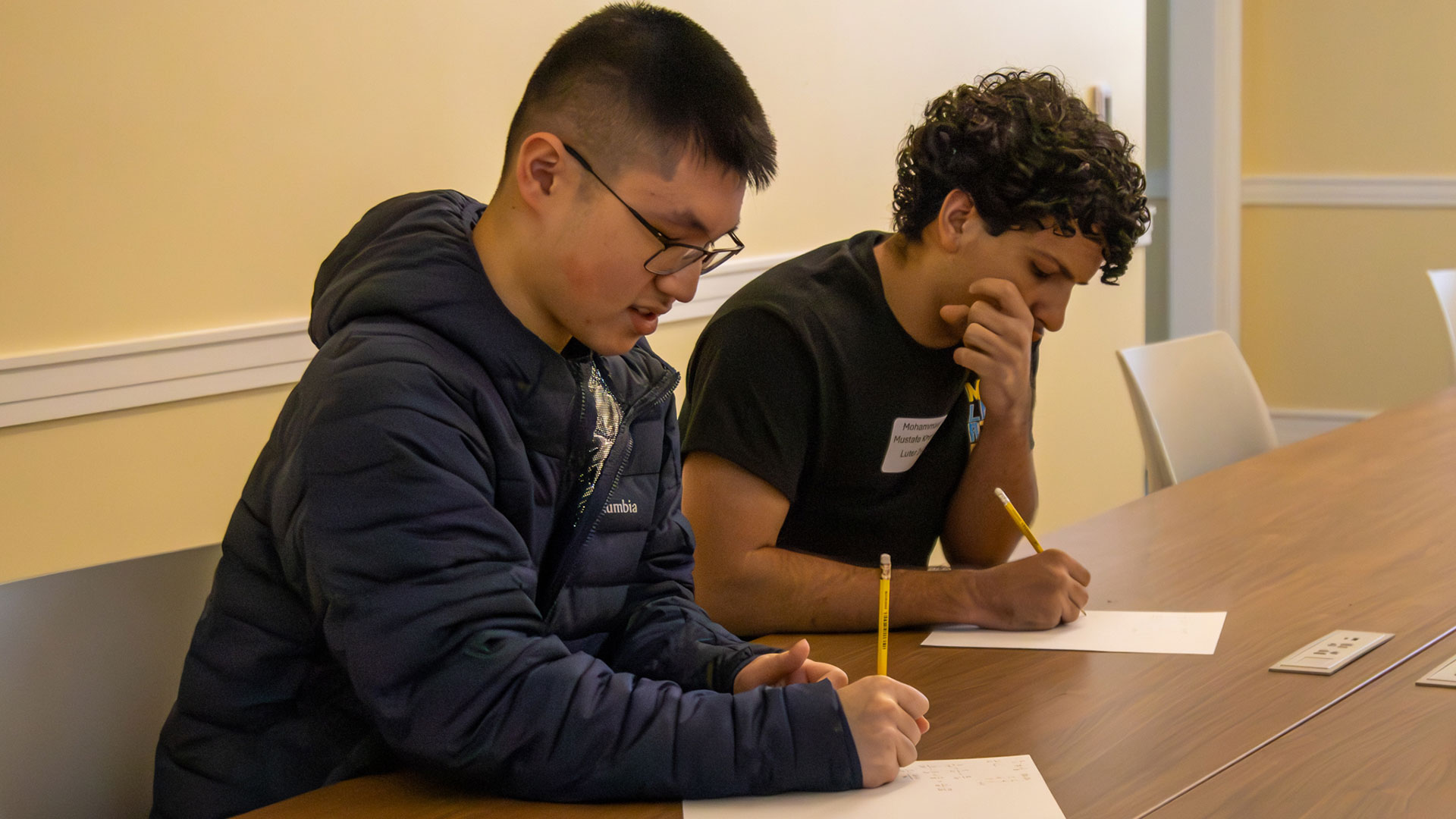 Two boys work on a problem on sheets of paper during the annual Regional Math Contest at CNU