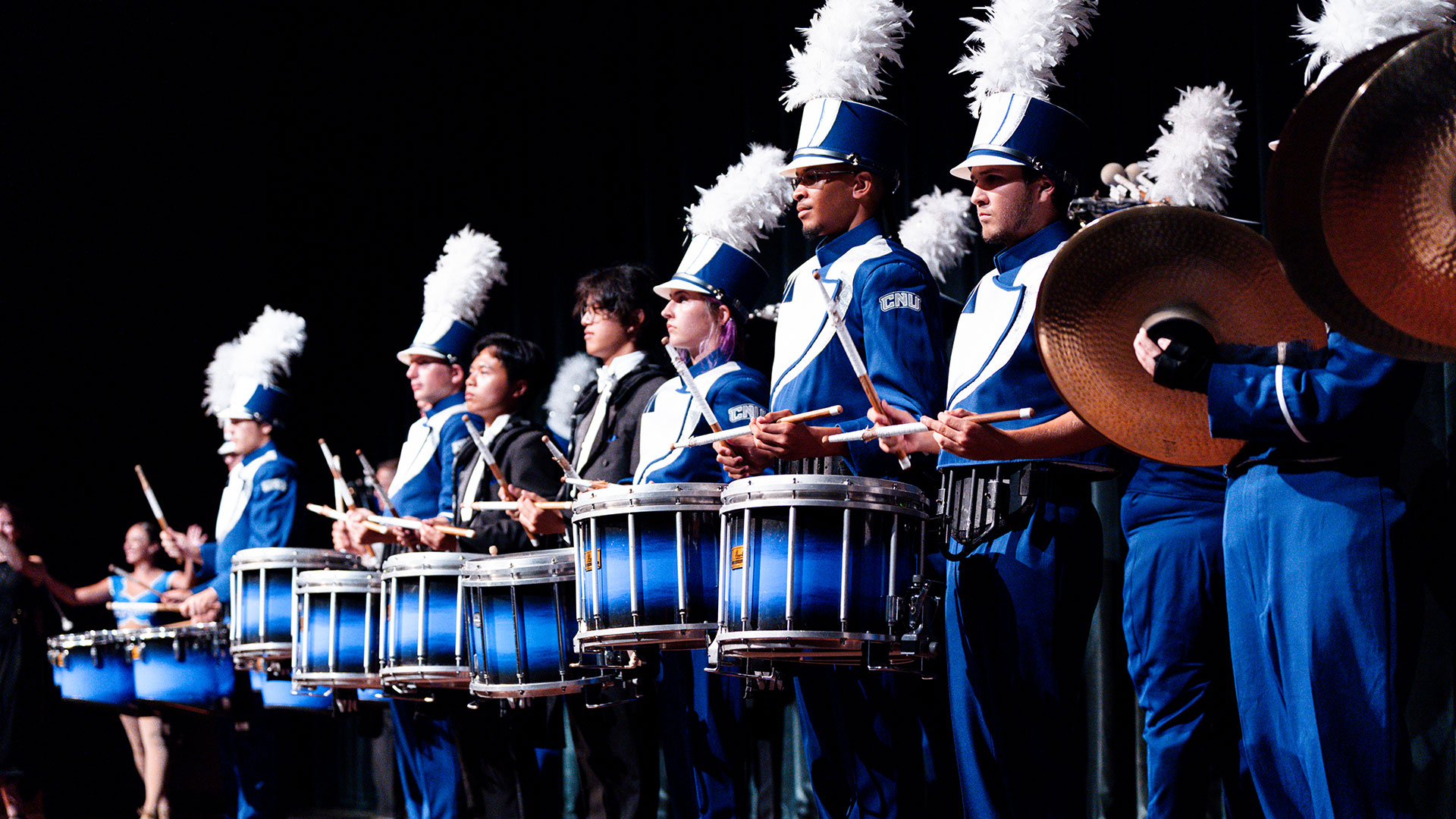 Members of CNU's Marching Captains marching band on stage in their uniforms