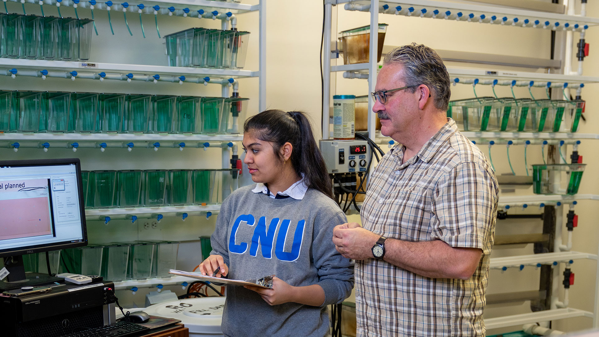 Student and Dr. Drew Velkey record observations in the psychology fish lab