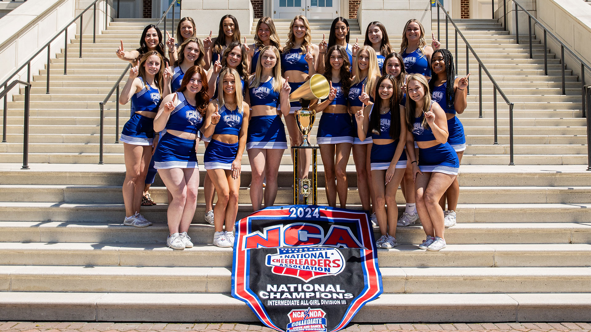 The CNU Competition Cheerleading squad poses in uniform with their trophy and banner