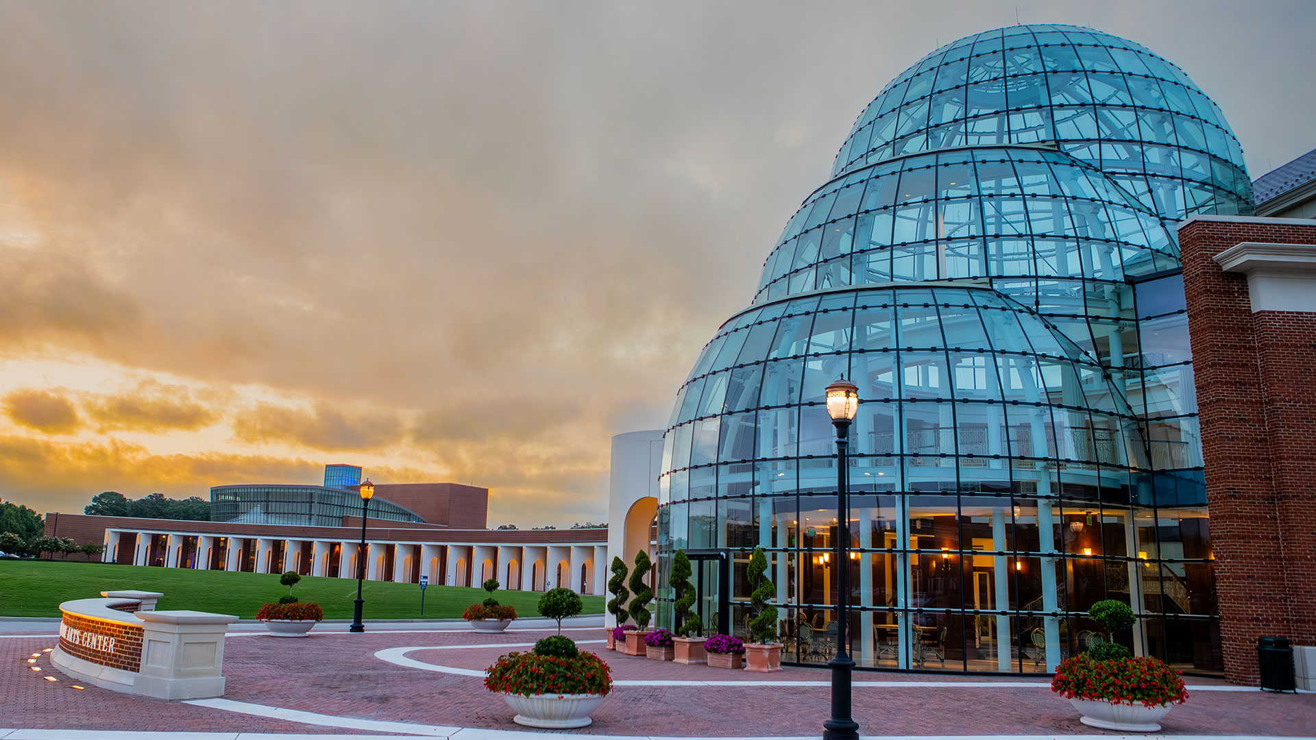 A side view of the Torggler Fine Arts Center's three glass domes as the sun begins to rise. The Ferguson Center for the Arts is in the background