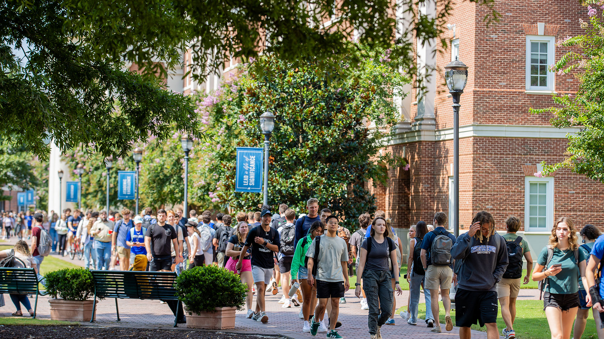 A crowded walkway on the campus of Christopher Newport University during a warm and sunny day