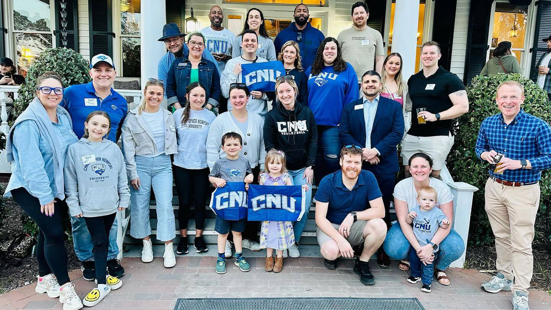 A group of CNU alumni with family members and staff on the steps of a building