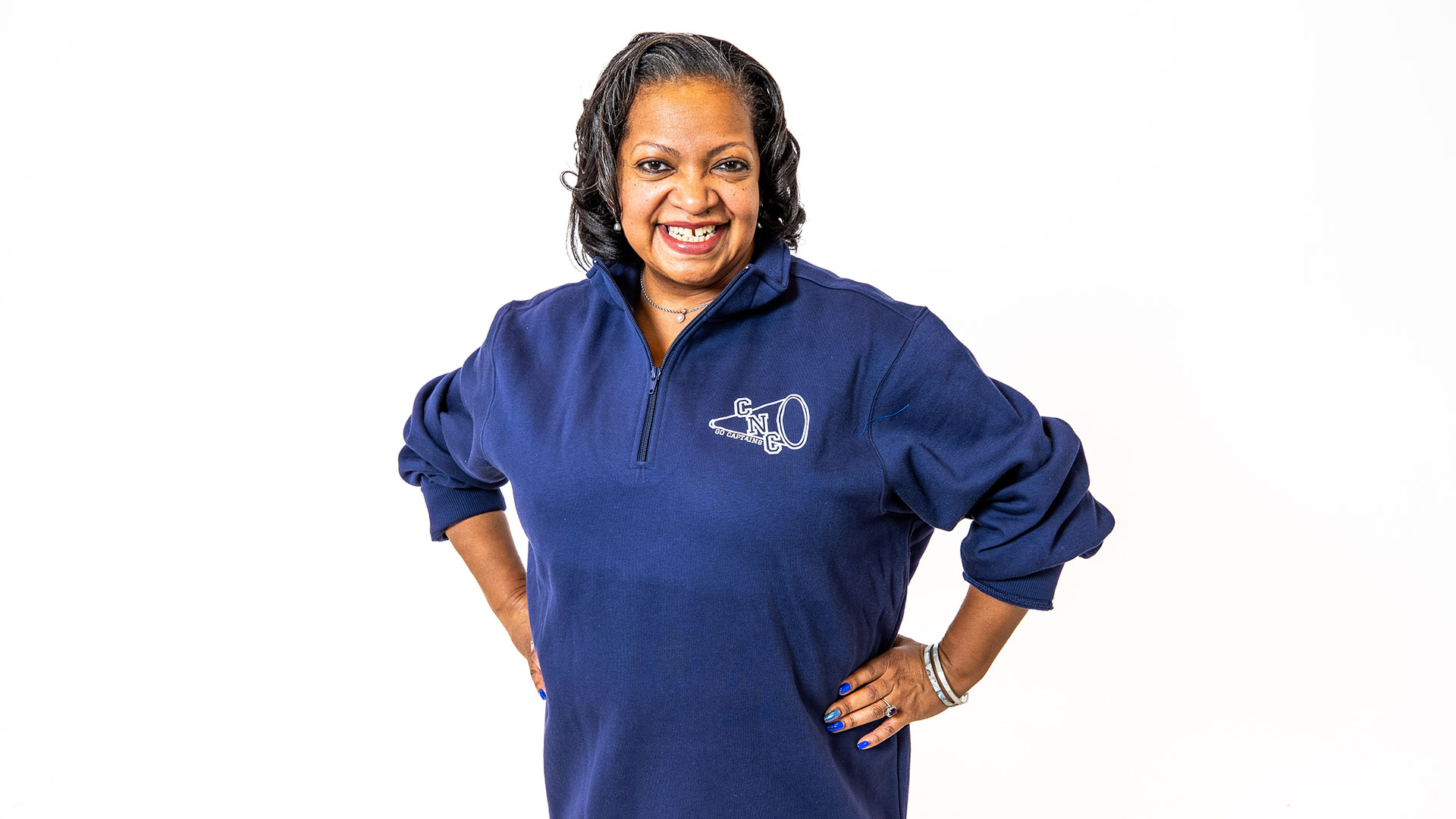 A woman wears a navy blue quarter zip with a megaphone and the letters CNC on the right side